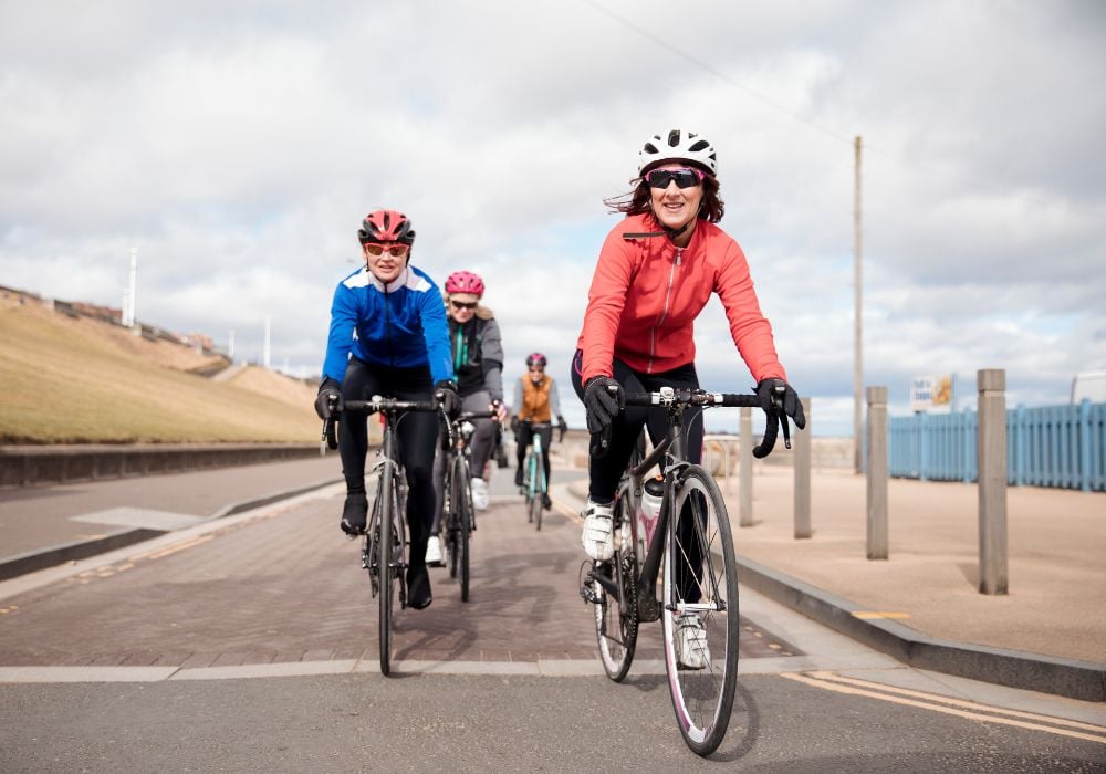 Group of female cyclists riding their bikes on a road.