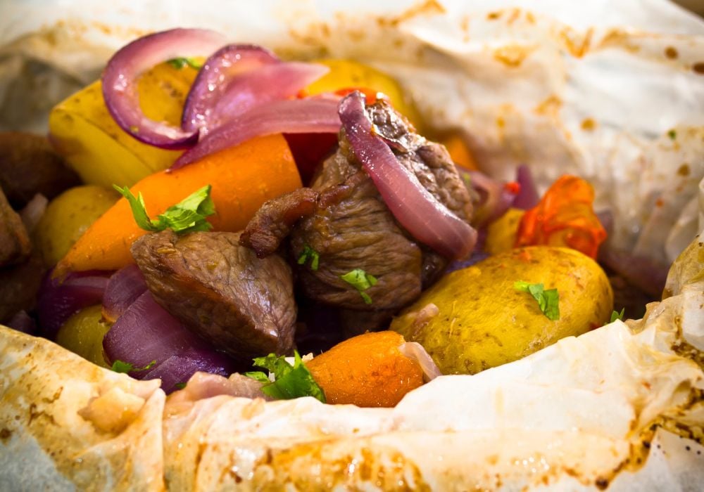 a tender and hearty lamb dish with some sliced of onions and carrots called kleftiko