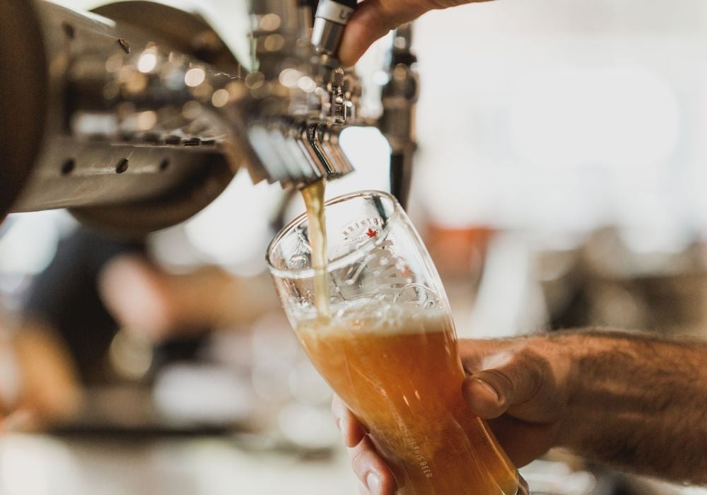 A bartender pours a pint of beer.